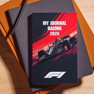 May include: A journal with a Formula 1 racing theme. The cover features a race car illustration with the text "MY JOURNAL RACING 2026" in white. The background is black and red with the F1 logo in white. The journal is on top of other notebooks.