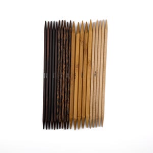 Könnte beinhalten: Eine Sammlung von Stricknadeln mit doppelten Spitzen in verschiedenen Braun- und Beigetönen. Die Holzstricknadeln sind vertikal vor einem weißen Hintergrund angeordnet. Die Größen sind aufgedruckt.