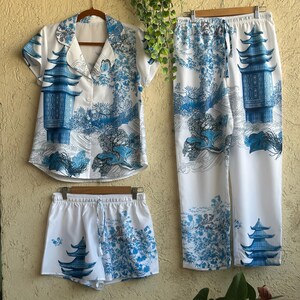 Op de afbeelding: Een witte pyjamaset met een blauwe en witte pagodeprint. De set bevat een shirt met korte mouwen, een short en een lange broek.