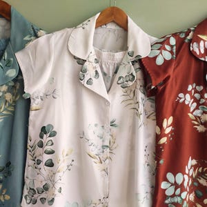 Può includere: Tre camicie a maniche corte con motivi floreali. Le camicie sono in tonalità di blu, bianco e ruggine.