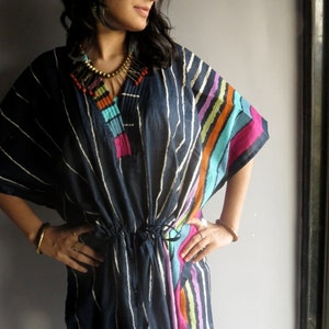 May include: A navy blue and white striped tunic with colorful stripes on the side. The tunic has a drawstring waist and a beaded necklace.