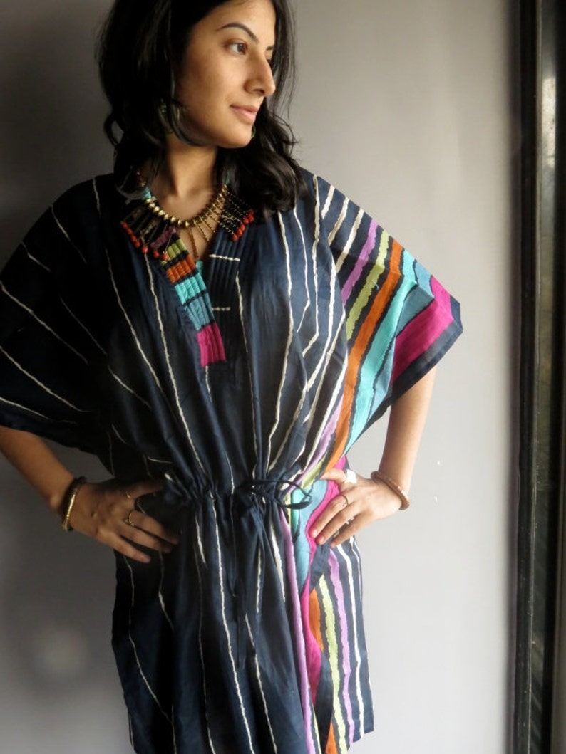 May include: A navy blue and white striped tunic with colorful stripes on the side. The tunic has a drawstring waist and a beaded necklace.