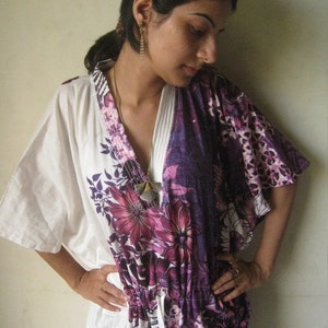 May include: A white and purple floral print kaftan with a V-neckline and a drawstring waist. The kaftan has a white background with purple and pink floral designs.