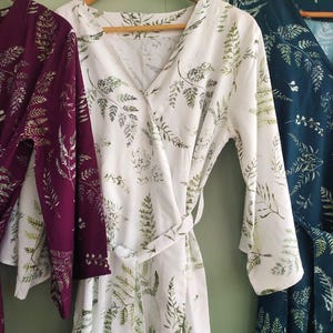 May include: Three long-sleeved robes with a floral print. The robes are in shades of burgundy, white, and teal.