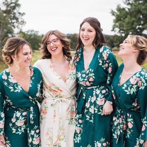 Può includere: Quattro donne indossano accappatoi con stampa floreale in tonalità di verde e bianco. Gli accappatoi hanno uno stile avvolgente e si legano in vita. Le donne sorridono e ridono insieme.
