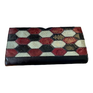 Könnte beinhalten: Eine schwarze Leder-Clutch mit einem geometrischen Muster aus roter, weißer und schwarzer Schlangenhaut.
