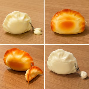 May include: A collection of four dumpling-shaped cases, each featuring a hinged design. Two cases are off-white with a smooth texture, while two are golden-brown with a toasted appearance. Each case includes a small metal clip and a miniature charm.