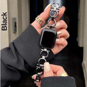 May include: Black Apple Watch band with a chain link design. The band is made of metal and has a silver finish.