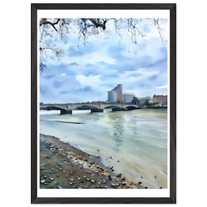 May include: A framed watercolor painting depicting a river scene with a multi-arched bridge spanning the water. In the background, modern buildings rise against a cloudy blue sky. The foreground shows a rocky riverbank and overhanging tree branches.