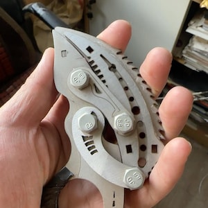 May include: A silver metal tool with a serrated edge and a handle. The tool has several small holes and a series of markings on the surface. The tool has the letters "JD" and the number "88" stamped on it.