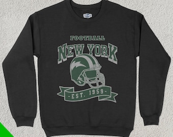 May include: Black sweatshirt featuring a green and white football helmet design. The text reads "FOOTBALL NEW YORK - EST. 1959-". The garment has a crew neck and long sleeves. The Fan Ghoul logo is in the upper right corner.