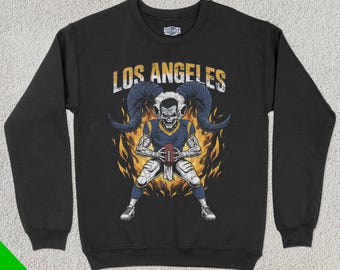 May include: Black sweatshirt with a graphic of a horned, skeletal football player holding a football. The text "Los Angeles" is above the graphic.