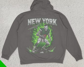 May include: A dark grey hooded sweatshirt with a graphic print of a football player in a green and white uniform. The text "NEW YORK" is printed above the graphic.