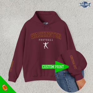 May include: Burgundy hooded sweatshirt with the text "WASHINGTON FOOTBALL" in orange and white. The sleeve has the text "CUSTOM PRINT" in orange.