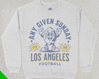May include: Grey sweatshirt with a blue and yellow graphic of a cartoon football with the text "Any Given Sunday" and "Los Angeles Football" with the years "Est. 1936".