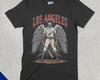 May include: Black t-shirt with a graphic of a skeleton baseball player with a halo and wings. The text "Los Angeles" is above the graphic.