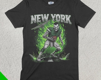 以下が含まれることがあります： 緑と白のグラフィックが描かれた黒いTシャツ。グラフィックは、フットボールを持ったスケルトンのフットボール選手が描かれており、緑色の炎に囲まれています。グラフィックの上には「NEW YORK」の文字があります。
