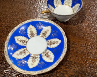 Kobaltblauwe theekop met bladmotief uit bezet Japan, met schoteltje van UCAGCO.