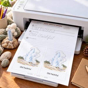 May include: A white printer outputting a worksheet titled Trace, Write & Explore. The page features the text Old Faithful in print and cursive, alongside two illustrations of the Old Faithful geyser erupting with blue and white water.