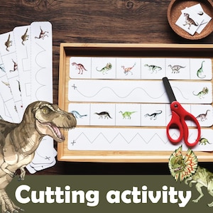 Puede incluir: Una bandeja de madera con tarjetas de actividades de corte con temática de dinosaurios y unas tijeras rojas. Las tarjetas presentan ilustraciones de dinosaurios y líneas punteadas para practicar el corte. El texto "Cutting activity" se muestra en la parte inferior.