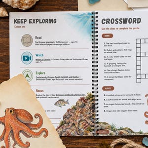 May include: A spiral-bound activity book open to a page titled Keep Exploring and Crossword, featuring educational text, icons, and an octopus illustration. The page includes sections for reading, watching, and exploring, alongside a crossword puzzle grid with clues about marine life.