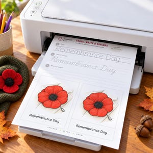 May include: A white printer holds a printed worksheet titled Trace, Write & Explore Remembrance Day. The page features cursive practice lines and two illustrations of red poppy pins with black centers, labeled Remembrance Day.