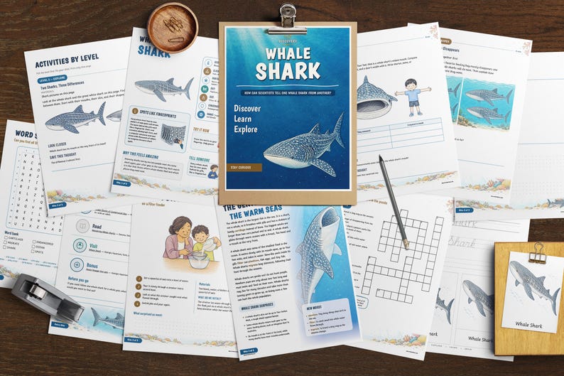 May include: A collection of educational worksheets about whale sharks, featuring illustrations, text, and activities. The central document on a clipboard is titled Whale Shark, with subheadings Discover, Learn, Explore. Includes a pencil and stapler.