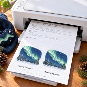 May include: A white printer outputting a worksheet titled Trace, Write & Explore Aurora Borealis. The page features cursive practice lines and two illustrations of the northern lights over a snowy pine forest with the text Aurora Borealis.