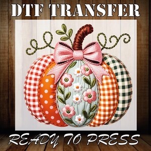 Peut inclure: Image DTF TRANSFER d'une citrouille décorative. La citrouille présente des sections à carreaux rouges, à pois orange et à carreaux verts. Un nœud rose et des broderies florales ornent le centre. Le texte "READY TO PRESS" est en bas.