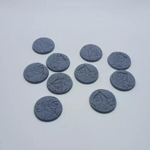 May include: Ten gray plastic miniature bases with a textured surface. The bases are round and have a diameter of approximately 25 mm.