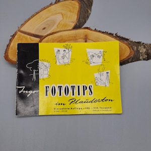 Puede incluir: Un folleto vintage titulado FOTOTIPS im Plauderton con una cubierta de color amarillo brillante que presenta dibujos de líneas negras de personas tomando fotografías. El texto incluye Vierzehnte Auflage - 186. - 215. Tausend y W 3444 - D 0/160.
