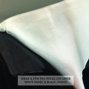 May include: A garment featuring a smooth white upper panel and a textured black lining. The fabric displays visible wear, specifically a few pin pricks on the upper white panel and the black lining, as noted by the text overlay on the image.