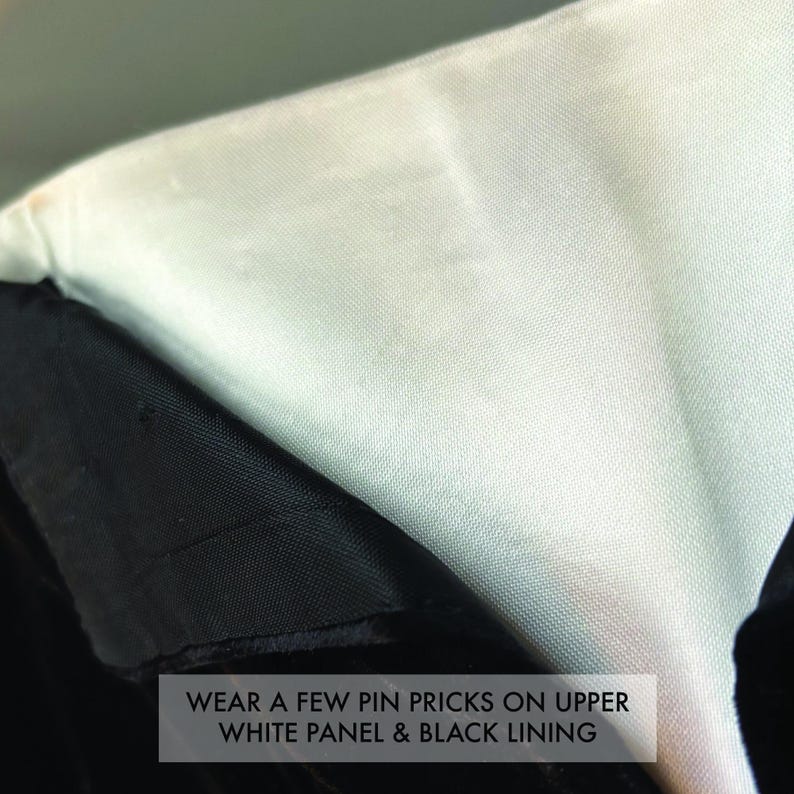 May include: A garment featuring a smooth white upper panel and a textured black lining. The fabric displays visible wear, specifically a few pin pricks on the upper white panel and the black lining, as noted by the text overlay on the image.