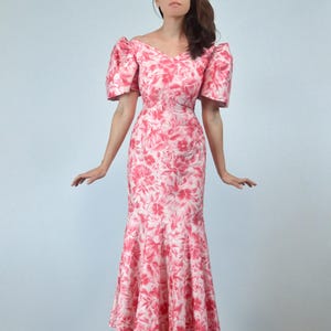 May include: A pink and white floral print dress with a fitted bodice and a flowing skirt. The dress has puffed sleeves and a V-neckline.