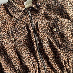 Pu&ograve; includere: Giacca marrone e nera con stampa leopardata, chiusura con cerniera, due tasche sul petto con bottoni e colletto. La giacca &egrave; in tessuto di velluto a coste.