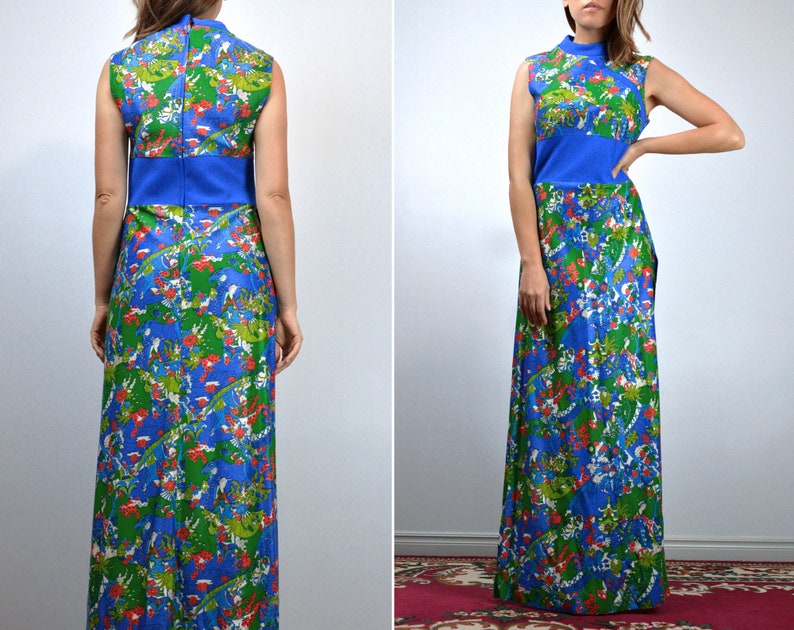May include: A sleeveless maxi dress with a high neckline. The dress has a blue bodice and a vibrant print of green, red, and white floral and abstract shapes on a blue background. The dress has a fitted waist and a long, flowing skirt.