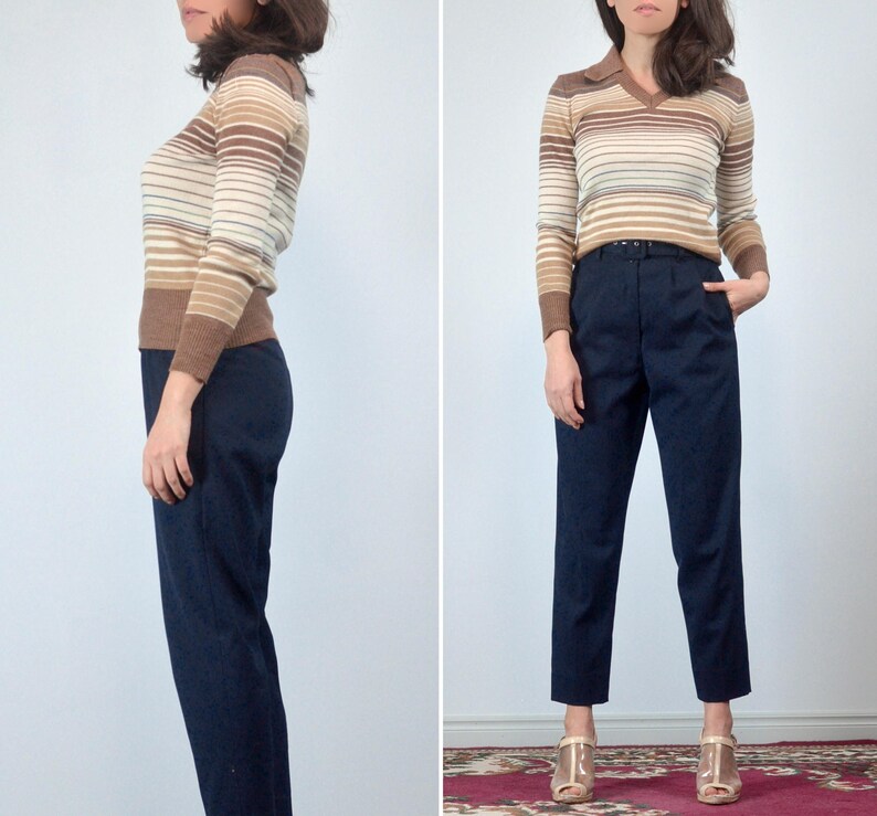 May include: A vintage outfit featuring a brown, tan, and cream striped long-sleeve sweater with a collared neckline. Paired with high-waisted, navy blue trousers. The outfit is completed with gold-colored heels.