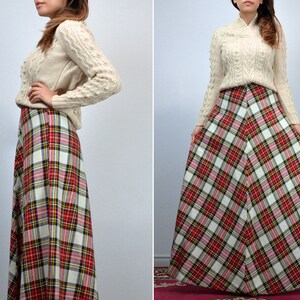 Puede incluir: Un su&eacute;ter de punto trenzado color crema combinado con una falda larga a cuadros. La falda presenta un patr&oacute;n de tart&aacute;n rojo, blanco, negro y amarillo. El conjunto es de estilo cl&aacute;sico y vintage.