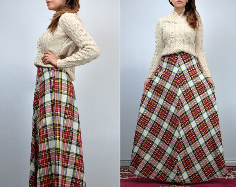 Puede incluir: Un su&eacute;ter de punto trenzado color crema combinado con una falda larga a cuadros. La falda presenta un patr&oacute;n de tart&aacute;n rojo, blanco, negro y amarillo. El conjunto es de estilo cl&aacute;sico y vintage.