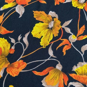 Puede incluir: Una tela negra con un patr&oacute;n floral con flores amarillas y naranjas. Las flores tienen un estilo vintage y est&aacute;n dispuestas en un patr&oacute;n repetitivo.