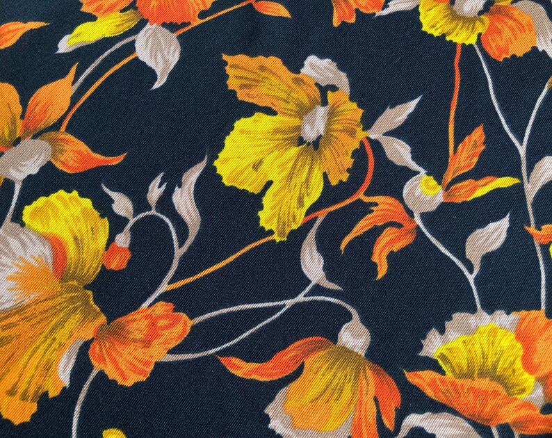 Puede incluir: Una tela negra con un patr&oacute;n floral con flores amarillas y naranjas. Las flores tienen un estilo vintage y est&aacute;n dispuestas en un patr&oacute;n repetitivo.