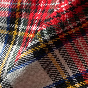 Puede incluir: Primer plano de una tela con un patr&oacute;n de cuadros cl&aacute;sico. El dise&ntilde;o presenta una combinaci&oacute;n de rayas rojas, negras, blancas, amarillas, verdes y azules. La tela tiene una apariencia texturizada, lo que sugiere un material duradero.
