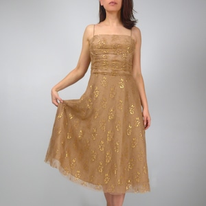May include: A vintage-style, knee-length dress in a golden-brown hue. The dress features a fitted bodice with delicate spaghetti straps and a gathered design. The skirt is adorned with gold floral embellishments, creating a shimmering effect. A classic piece for special occasions.