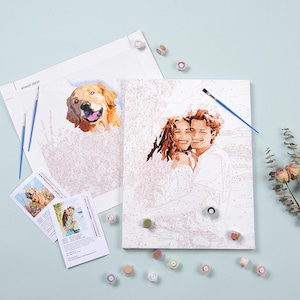 May include: A paint by numbers kit with two canvases, one featuring a couple and the other a golden retriever. The kit includes paint pots, brushes, and instructions.