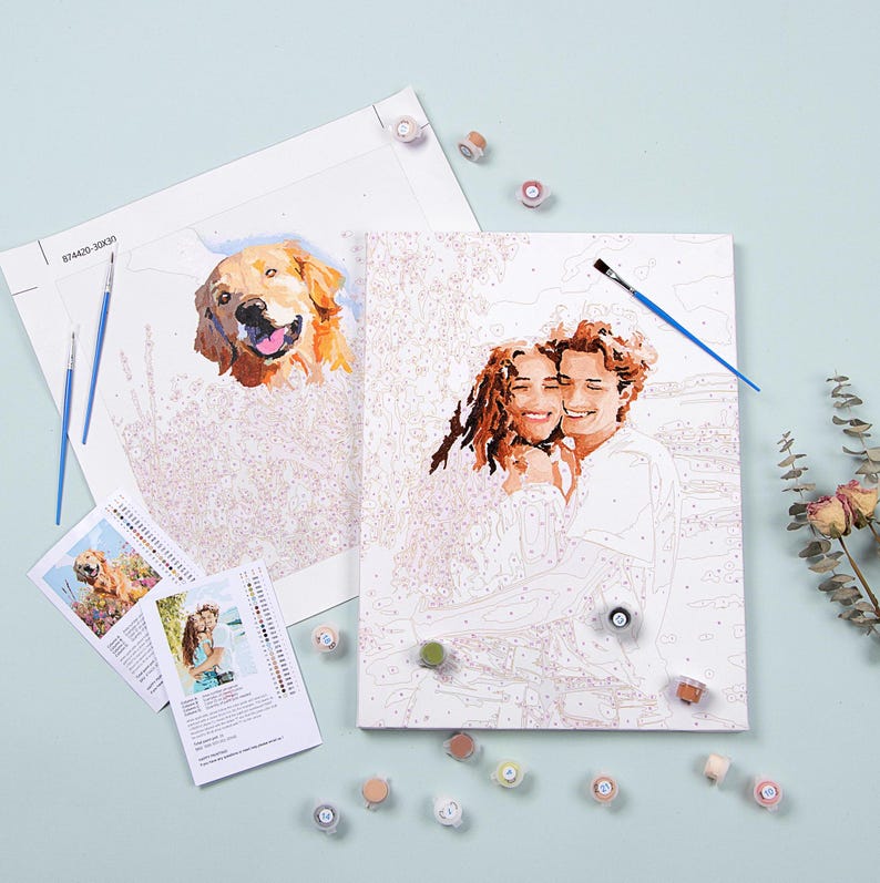 May include: A paint by numbers kit with two canvases, one featuring a couple and the other a golden retriever. The kit includes paint pots, brushes, and instructions.