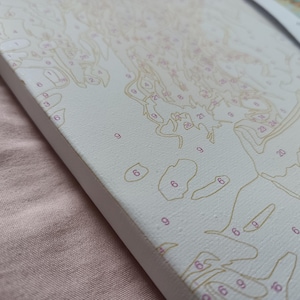 May include: A white canvas with a paint-by-numbers design. The design features a variety of shapes and numbers, including 6, 9, 20, and 23.
