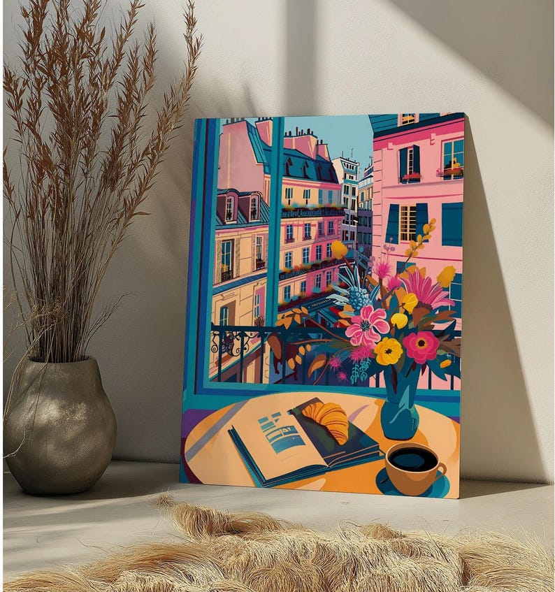 Peut inclure: Une peinture color&eacute;e d'une sc&egrave;ne de rue parisienne avec une vue sur les b&acirc;timents et un balcon. Un bouquet de fleurs dans un vase bleu est pos&eacute; sur une table avec un livre et une tasse de caf&eacute;.