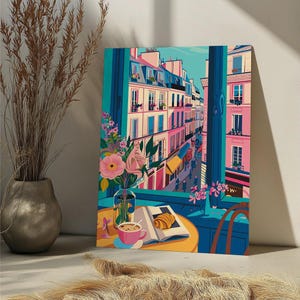 Peut inclure: Une peinture color&eacute;e d'une sc&egrave;ne de rue parisienne vue d'une fen&ecirc;tre. La peinture repr&eacute;sente un caf&eacute; avec une marquise jaune, un croissant sur un livre et une tasse de caf&eacute; sur une table. La rue est bord&eacute;e de b&acirc;timents roses et jaunes.