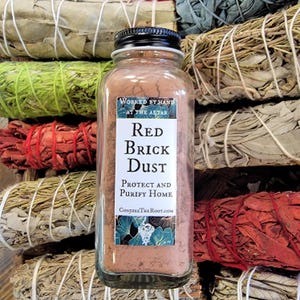 May include: A glass jar with a black lid filled with red brick dust. The label reads "Worked by Hand at the Altar, Red Brick Dust, Protect and Purify Home, ConjureTheRoot.com".
