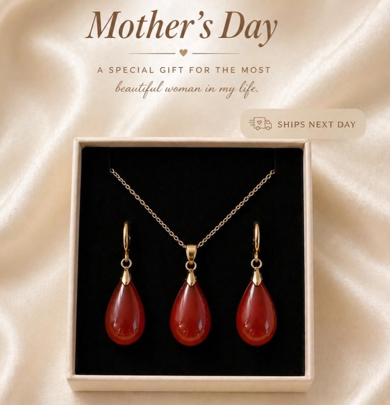 K&ouml;nnte beinhalten: Ein goldfarbenes Halsketten- und Ohrring-Set mit tropfenf&ouml;rmigen, rot-orangen Anh&auml;ngern, pr&auml;sentiert in einer Geschenkbox. Der Text "Mother's Day" und "A special gift for the most beautiful woman in my life" sind im Bild zu sehen.